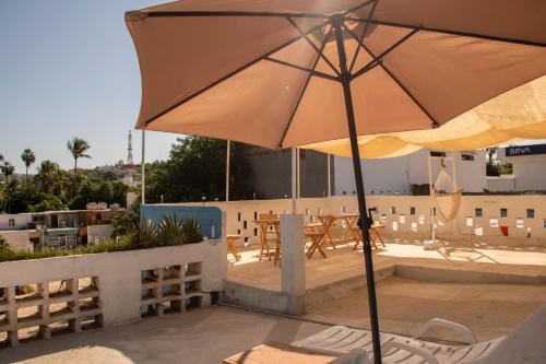 um pátio com um guarda-sol, cadeiras e mesas em Hotel Casa Ceci Inn em San José del Cabo
