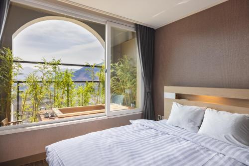 a bedroom with a bed and a large window at KensingtonResort JirisanHadong in Hadong