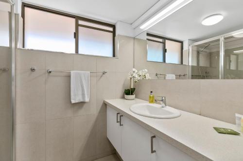 a bathroom with a sink and a mirror at The Noosa Apartments in Noosa Heads