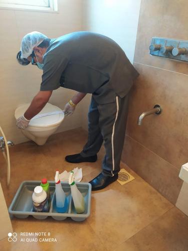 a man standing in a bathroom with a toilet at Hotel Plaza in Mumbai