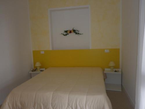 a bedroom with a bed with a yellow wall at Villa Al Mare Guest House in Tre Fontane