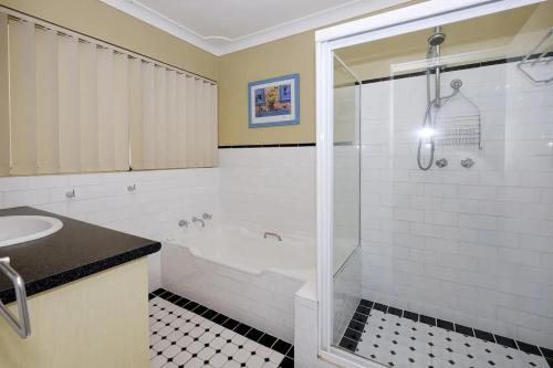 Un baño con bañera, lavabo y ducha. en Retreat on Gleeson, en Forster