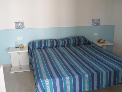 a bedroom with a bed with a blue and white stripes at Villa Al Mare Guest House in Tre Fontane