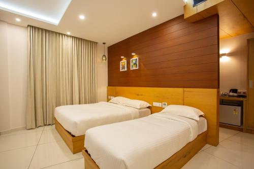 two beds in a hotel room with wooden walls at Hasco Tower in Palakkad