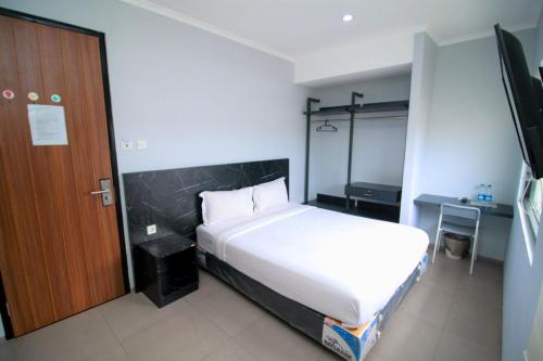 um quarto com uma cama branca e uma porta de madeira em Bale Resident em Jakarta