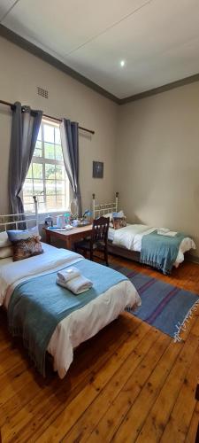 a bedroom with two beds and a table and a desk at Bo Kamer Guesthouse in Ermelo