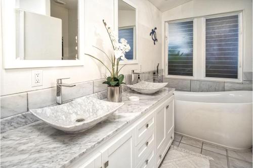 Un baño blanco con dos lavabos y una bañera. en Kololia Living by Casago Kona - Your Private, Hawaiin Home with Pool, en Kailua-Kona