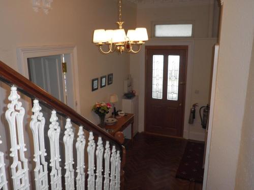 a hallway with a staircase and a chandelier at Douglas Park Guest House in Dunoon