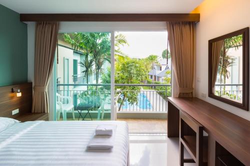 a bedroom with a bed and a large window at Parida Resort in Bang Tao Beach