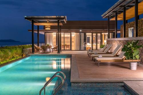 an outdoor pool with lounge chairs and a house at 1 Hotel Haitang Bay, Sanya in Sanya