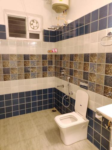 a bathroom with a toilet and blue tiles at KSTDC Hotel Mayura Gerusoppa, Jogfalls in Māvingundi