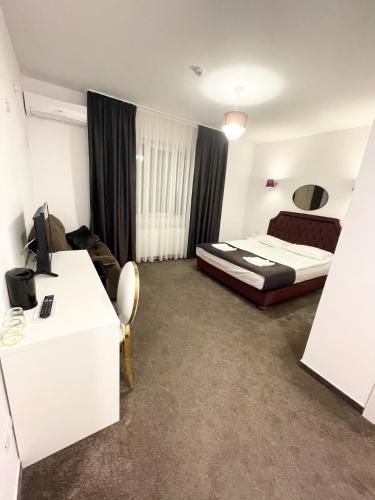 a bedroom with a bed and a desk with a computer at COCHET BOUTIQUE in Târgu Jiu