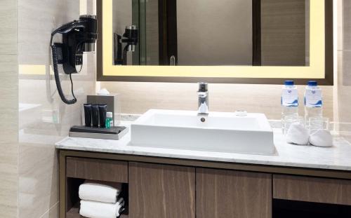 a bathroom with a white sink and a phone at GRAMM HOTEL by Ambarrukmo Yogyakarta in Yogyakarta