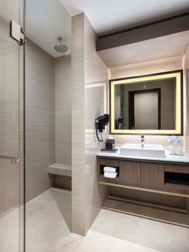a bathroom with a sink and a mirror at GRAMM HOTEL by Ambarrukmo Yogyakarta in Yogyakarta
