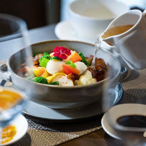 a bowl of soup on a table with a cup of coffee at GRAMM HOTEL by Ambarrukmo Yogyakarta in Yogyakarta