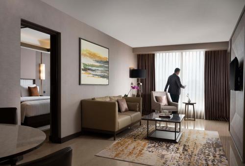 a living room with a man standing in a hotel room at GRAMM HOTEL by Ambarrukmo Yogyakarta in Yogyakarta