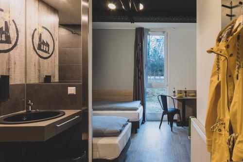 a bathroom with a sink and a room with two beds at Das Schlafwerk Stuttgart-Nord VOLLDIGITALES HOTEL - Self-check-in -LowBudget in Korntal-Münchingen