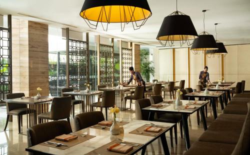 a restaurant with tables and chairs and people in the background at GRAMM HOTEL by Ambarrukmo Yogyakarta in Yogyakarta