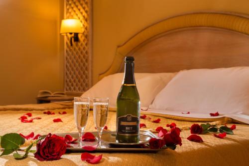 a bottle of champagne and two glasses on a bed at Best Western Park Hotel Roma Nord in Fiano Romano