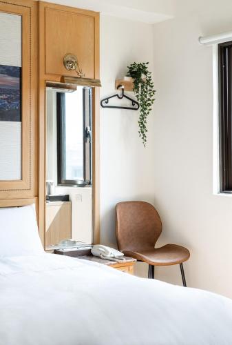 a bedroom with a bed and a chair and a window at 二川行旅 - HiRiver Hotel in Taichung