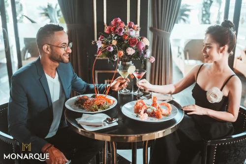 a man and a woman sitting at a table eating food at Monarque Hotel Danang in Da Nang