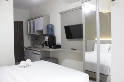 a hotel room with two beds and a tv at Stylish Studio Apartment at Harvard Jatinangor near ITB By Travelio in Sayang