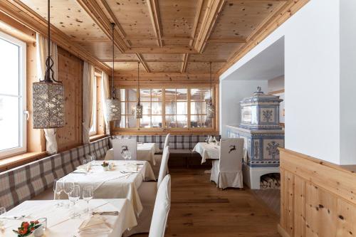 a restaurant with white tables and a clock on the wall at Superior Hotel Panorama in Obertauern