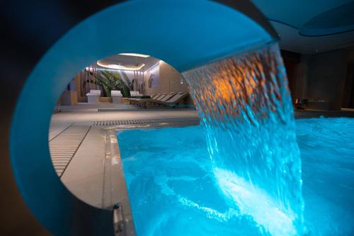 a swimming pool with a blue water fountain at Hotel Belmont & Spa in Sinaia