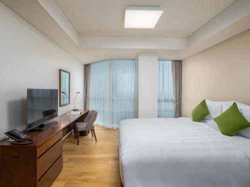a hotel room with a bed and a desk and a television at LOTTE Hotel Serviced Apartment in Yangon