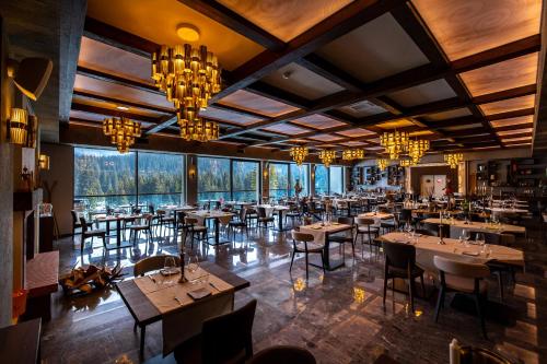 a restaurant with tables and chairs and chandeliers at Hotel Belmont in Sinaia