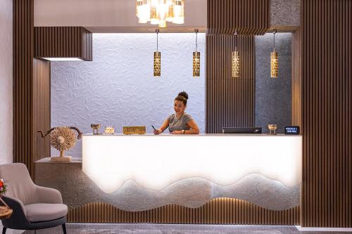 una mujer está parada detrás de una gran bañera blanca en Hotel Belmont, en Sinaia