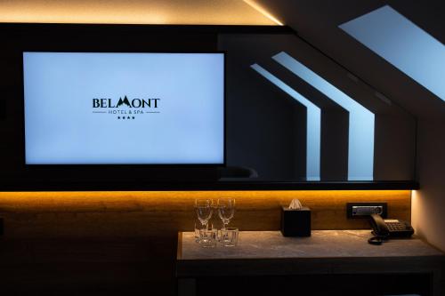a table with glasses and a phone and a screen at Hotel Belmont & Spa in Sinaia