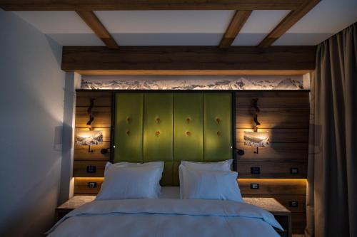 a bedroom with a green headboard and two white pillows at Hotel Belmont & Spa in Sinaia