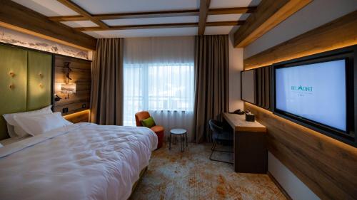 a hotel room with a large bed and a flat screen tv at Hotel Belmont & Spa in Sinaia