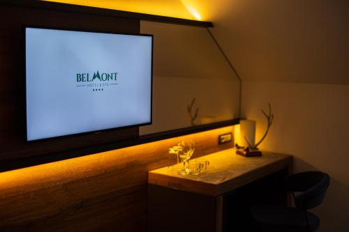 a flat screen tv in a room with a table with glasses at Hotel Belmont & Spa in Sinaia