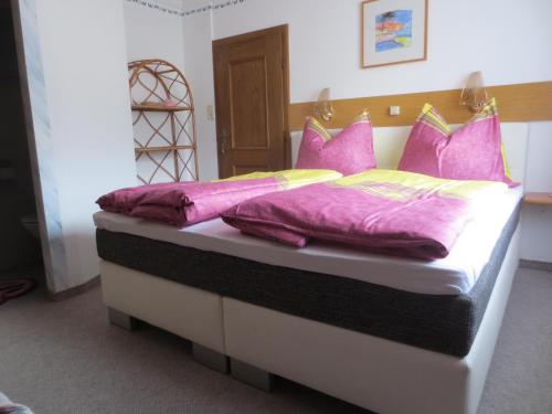 a bed with pink and yellow pillows on it at Gästehaus Scharler in Neukirchen am Großvenediger