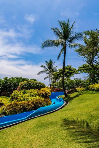 a river with a palm tree in a park at Grand Hyatt Bali in Nusa Dua