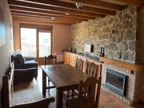 a living room with a table and a stone fireplace at Mirasierra II Y III in Navarredonda de Gredos