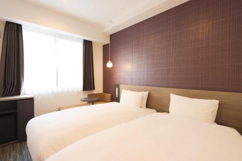 a hotel room with two beds and a window at Wander Kyoto Nanajo in Kyoto