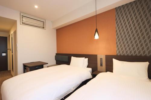 two beds in a hotel room with white sheets at Wander Kyoto Nanajo in Kyoto