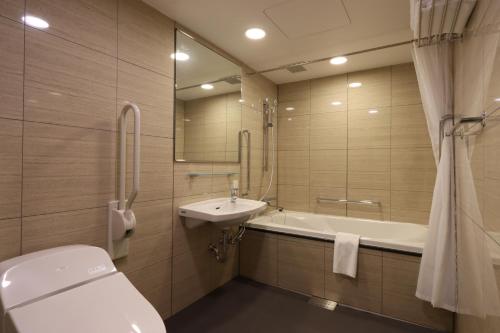 a bathroom with a toilet and a sink and a tub at Wander Kyoto Nanajo in Kyoto