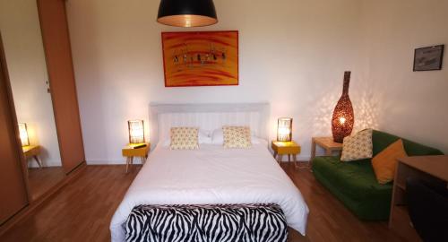 Un dormitorio con una cama y un sofá verde. en La Villa des Coteaux, en Pomport