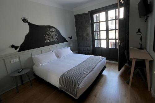 a bedroom with a bed and a desk and a window at H Complutum in Alcalá de Henares