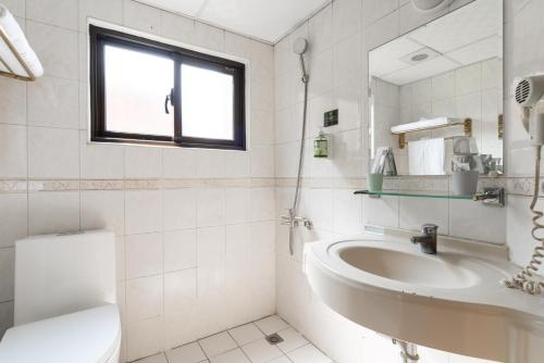 a white bathroom with a sink and a toilet at 二川行旅 - HiRiver Hotel in Taichung