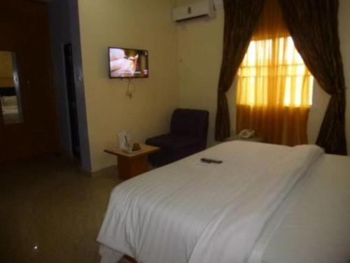 a bedroom with a bed and a chair and a television at Nera Hotels in Jabi