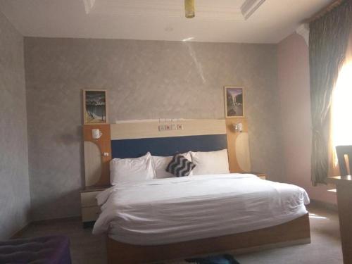 a bedroom with a large white bed with a blue headboard at Nera Hotels in Jabi