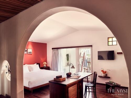 a hotel room with a bed and a desk and a window at The Myst Dong Khoi in Ho Chi Minh City