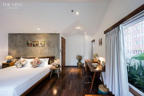 a bedroom with a bed and a desk and a window at The Myst Dong Khoi in Ho Chi Minh City