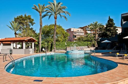 a large pool with blue water and palm trees at BQ Augusta Hotel in Palma de Mallorca