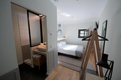 um pequeno quarto com uma cama e um espelho em H Complutum em Alcalá de Henares